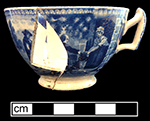 Pearlware handled cup printed underglaze in medium blue with genre scene.  Continuous repeating floral interior rim. 4” rim diameter; 2.5” vessel height.